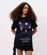 Remera negra de algodón con cuello redondo, mangas cortas y estampa frontal de la saga Harry Potter con ilustración nocturna del castillo de Hogwarts y el texto First Years This Way.