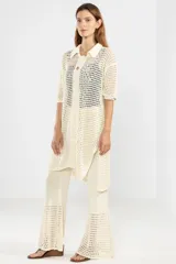 Camisa larga de punto abierto color crema, con cuello clásico, manga corta y cierre frontal con botones.