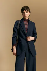 Blazer de corte sastrero con solapas clásicas y estructura definida. Presenta un diseño versátil con silueta ligeramente oversized, ideal para un estilo sofisticado y atemporal.
