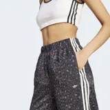 Pantalón Adidas Originals wide leg de satén, con estampado animal print en tonos grises y negros, cintura elástica y las clásicas tres tiras blancas a lo largo de los laterales.