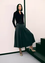 Cardigan de punto acanalado color negro, con cuello en V y detalle de pelo sintético en el cuello. Presenta cierre frontal con botones, diseño entallado y manga larga.