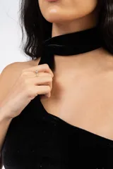 Top asimétrico de terciopelo negro con destellos brillantes, diseño de un solo hombro y cuello tipo choker integrado.
