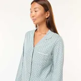 Conjunto de pijama largo celeste con estampado de lunares blancos. Incluye camisa de manga larga con cuello y botones, y pantalón de corte recto.