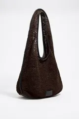 Bolso de hombro de estructura blanda confeccionado en tejido de algodón trenzado color marrón, con detalles de ribetes y asa en piel ovina negra. Presenta una silueta amplia y etiqueta logotipada de la marca en la parte inferior.