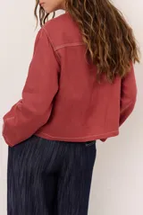 Chaqueta de lino color beige, de manga larga, con cuello redondo y cierre frontal de botones a presión con solapa.