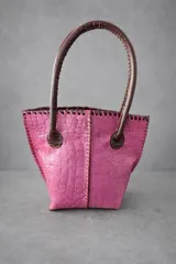 Cartera de cuero con textura crocco en color rojo, de silueta estructurada, manijas largas marrones y detalles de terminación artesanal en el borde superior.