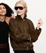 Campera de gamuza sintética color marrón, con cuello inglés, cierre frontal con botones metálicos, bolsillos delanteros y elástico en el bajo y puños.