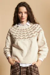 Sweater de tejido jacquard en color crema con diseño geométrico en tonos marrones en la zona del cuello y hombros. Presenta cuello redondo, mangas largas con puños acanalados y un corte holgado.