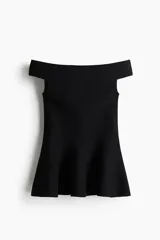 Top largo de punto tupido, color negro, con hombros descubiertos, corte ajustado y diseño acampanado estilo peplum desde la cintura.