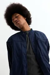 Campera tipo bomber color beige, confeccionada en nylon, con cierre frontal, cuello, puños y ruedo acanalados.