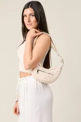 Cartera tipo baguette color crema, de ecocuero matelassé con cierre frontal y correa regulable.