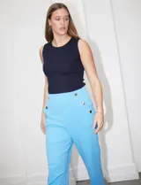 Pantalón naranja de crepe elastizado, corte recto, con bolsillos delanteros y apliques de botones metálicos.