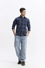 Camisa de manga larga confeccionada en viyela de algodón con diseño de cuadros en tonos azules y líneas finas en beige. Presenta cierre frontal con botones, cuello clásico y un bolsillo en el pecho.