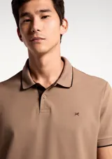 Remera polo blanca de manga corta, con cuello camisero y ribetes grises en cuello y puños. Cuenta con cierre frontal de botones y un pequeño logo bordado en el pecho.