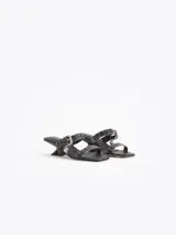 Sandalias de cuero vacuno efecto gastado color negro, con taco de 4 cm, tiras con mini tachas, hebilla metálica y dijes colgantes.