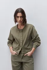 Campera azul marino de algodón, de corte relajado y largo corto, con cuello redondo, cierre frontal con botones metálicos, bolsillos delanteros y mangas largas con puños ajustables.