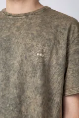 Remera de algodón con efecto de lavado desgastado tipo snow wash, de corte semi-oversize, cuello redondo y manga corta. Presenta un pequeño estampado gráfico circular en el pecho.