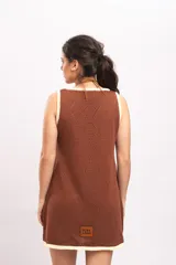 Vestido corto de punto color marrón, de corte suelto y sin mangas, con escote en V y detalles en tono marfil en el cuello, sisas y ruedo.