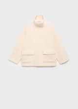 Chaqueta de bouclé color beige con cuello alto, cierre frontal oculto con cremallera y botones a presión, bolsillos con solapa en los laterales y manga larga.