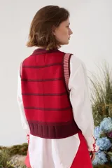 Chaleco tejido de punto sin mangas, con rayas horizontales azul marino y blancas, cierre frontal con botones y terminaciones en crochet rojo.
