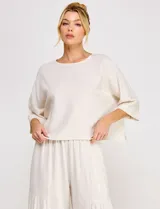 Blusa corta color beige de lino y viscosa, con escote redondo, mangas tres cuartos estilo kimono y corte holgado.