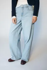 Jeans de tiro medio con diseño wide leg y pernera ancha. Presenta cinco bolsillos, cierre frontal con cremallera y botón, y detalle de raya planchada en el delantero y la espalda.