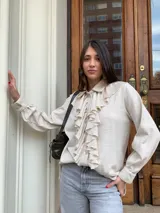 Camisa color crema de lana tejida con cuello camisero y volados frontales.