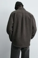 Sobrecamisa de corte relajado confeccionada en tejido de algodón con textura. Presenta cuello solapa, cierre frontal con botones, manga larga con puños abotonados y un bolsillo plastrón en el pecho.