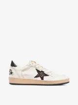 Zapatillas deportivas de cuero color blanco con detalles en negro y estrella de glitter color borgoña.