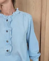 Blusa de manga larga con estampado de rayas verticales finas en tono beige. Presenta cuello redondo con volados, cierre frontal parcial con botones y puños con volados.