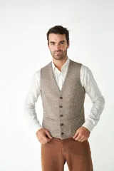 Chaleco de vestir para hombre, color marrón claro con textura tweed. Diseño sastrero con cuello en V, cierre frontal con botones, bolsillos ribeteados y forro interno. Confeccionado en lana fina sin teñir, diseñado exclusivamente por Don Baez.