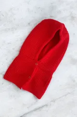 Balaclava de tejido de punto en color rojo, con diseño envolvente y cierre frontal mediante botones metálicos.