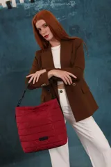 Cartera tipo tote de diseño capitoneado con patrón geométrico triangular. Presenta un acabado acolchado, asa de mano resistente y cierre superior. Incluye una etiqueta decorativa en la parte inferior frontal.