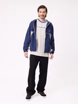 Rompevientos Rusty con capucha, diseño bicolor en azul marino y gris, cierre frontal y logo bordado en el pecho.