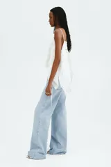 Jean wide leg de tiro alto en denim de algodón celeste claro, con diseño de cinco bolsillos, cierre de cremallera y botón metálico.