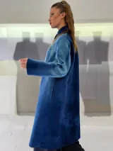 Tapado largo de fieltro de lana merino con teñido artesanal tie-dye en degradé de azul. Tiene cuello alto, cierre lateral con broches ocultos, bolsillos laterales y corte amplio.