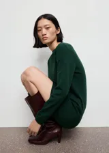 Vestido corto de punto fino color verde oscuro, con cuello redondo y manga larga, de diseño recto.