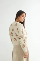 Cardigan de punto con estampado de flores, cuello redondo y cierre frontal con botones. Presenta un diseño de corte holgado con puños y ruedo acanalados.
