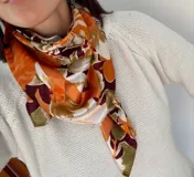 Pañuelo cuadrado de seda con estampado floral en tonos naranja, borra de vino, beige y blanco.