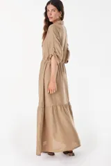 Vestido camisero largo de lino italiano color celeste, de corte relajado, con mangas caídas, jareta ajustable en la cintura, cierre frontal de botones y bajo con volado fruncido.
