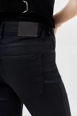 Pantalón de jean negro de corte skinny y tiro alto, confeccionado en gabardina con elastano y recubrimiento que simula cuero.