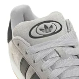 Championes Adidas Campus 00s de diseño retro, confeccionados en gamuza gris con las clásicas tres tiras laterales en cuero negro, cordones anchos y suela de goma color miel.