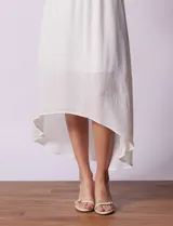 Vestido midi blanco de gasa bambula marca Lily Black, con escote redondo, breteles regulables y lazo de ajuste. Presenta una sobrecapa en el torso y un forro interno a tono. El largo de la espalda es mayor al largo delantero.