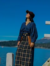 Falda larga de lana con estampado tweed a cuadros en tonos marrón y negro. Presenta detalles de cuero marrón en los bolsillos laterales y botón de guampa en la cintura.