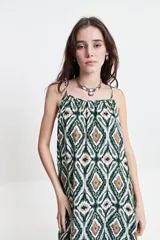 Vestido largo de silueta amplia con breteles finos y escote redondeado. Presenta un diseño fluido con frunces sutiles en el escote delantero y trasero, confeccionado en tela estampada con motivos geométricos.
