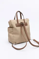 Mochila negra de poliéster texturizado con superficie acanalada. Cuenta con asas superiores marrones, tiras regulables para la espalda, bolsillo frontal con cierre metálico, compartimentos laterales y un interior amplio.