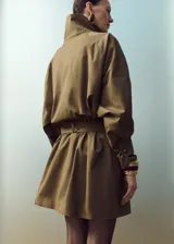 Chaqueta marrón de cuello alto con cierre de botones desplazados, mangas largas abullonadas y cinturón ajustable del mismo tejido.