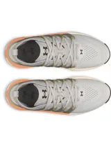 Championes Under Armour Phantom X, de color gris con detalles en naranja y suela blanca y negra. Presentan una estructura de soporte lateral semitransparente con el logo de la marca y cordones con detalles amarillos.