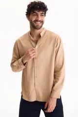 Camisa de manga larga color beige con cuello mao y cierre frontal con botones.