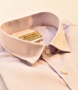 Camisa de vestir lisa color lila claro, de corte clásico, con cuello inglés y botones blancos.